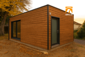 Garage en kit en bois naturel dans un jardin français, lumière dorée en fin de journée