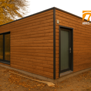 Garage en kit en bois naturel dans un jardin français, lumière dorée en fin de journée